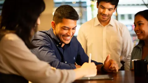 Colleagues together looking at a tablet in a plant-filled a office.