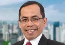 Portrait of Bayu Utomo, Director, Indonesia, outside in front of tall city buildings with blue skies.