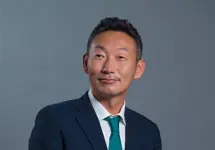 Portrait of Kajiura Hisanao, Managing Director, Japan, in blue suit against dark blue/grey background.